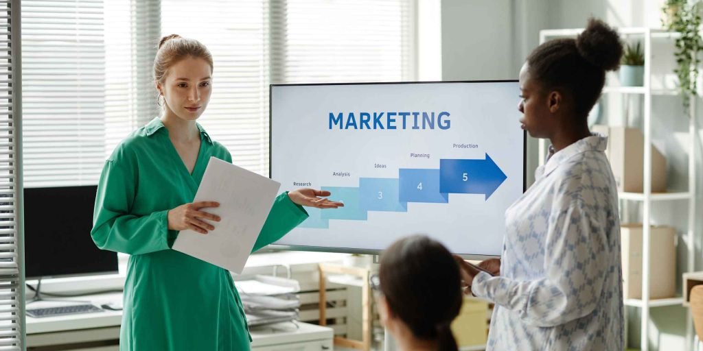 Three colleagues discussing a marketing funnel slide in an office